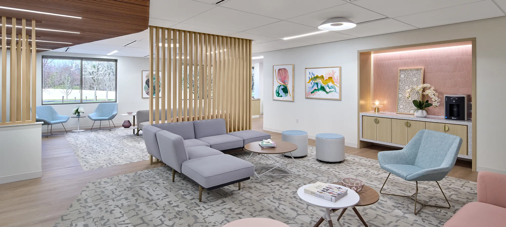 Modern healthcare facility waiting area with stylish furniture and abstract art, featuring light wood flooring and patterned carpet.