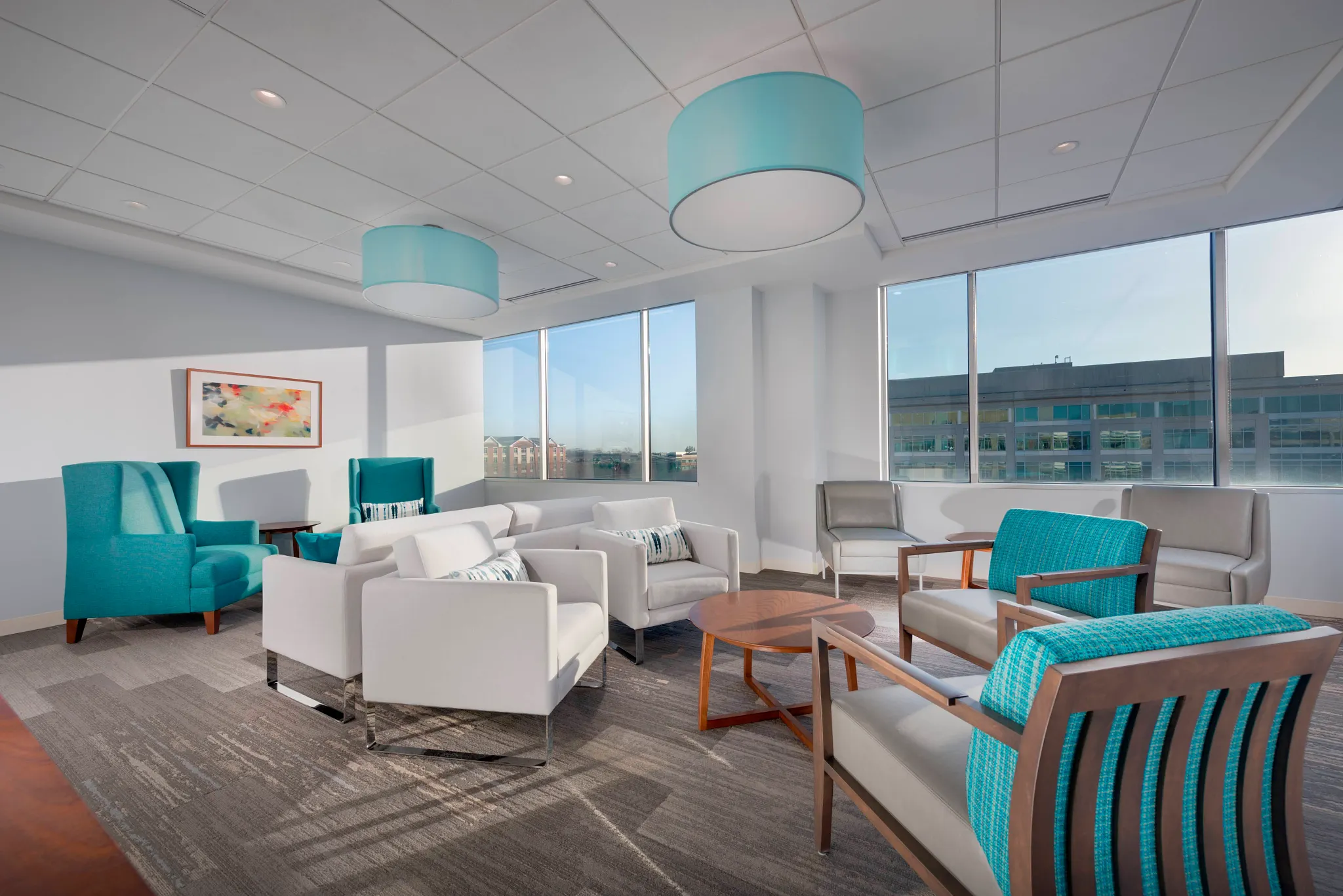 Modern healthcare facility waiting area with teal and white seating, featuring commercial carpet tile flooring in a neutral gray pattern