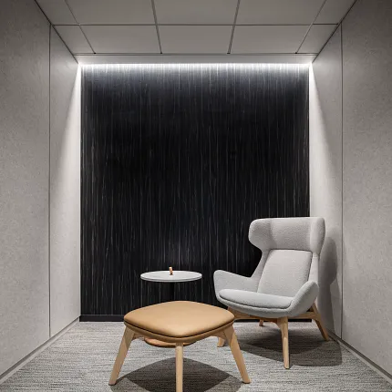 Contemporary Workplace Design with Gray Commercial Carpet Tile Flooring Modern office space with gray commercial carpet tile flooring, featuring a light gray armchair and a tan ottoman