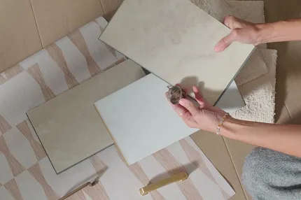 Beige and Cream Luxury Vinyl Tile Samples for Residential Flooring Hands holding beige and cream luxury vinyl tile samples on a patterned rug