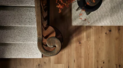Stylish hardwood flooring for warm home interiors Hardwood flooring with staircase and rug in a cozy interior