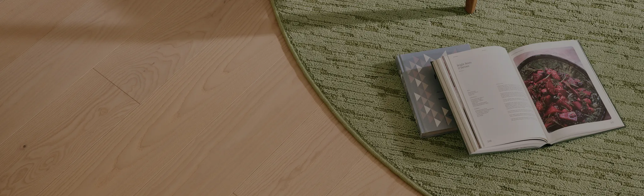 Geometric patterned carpet in shades of gray on light hardwood flooring with a black round table