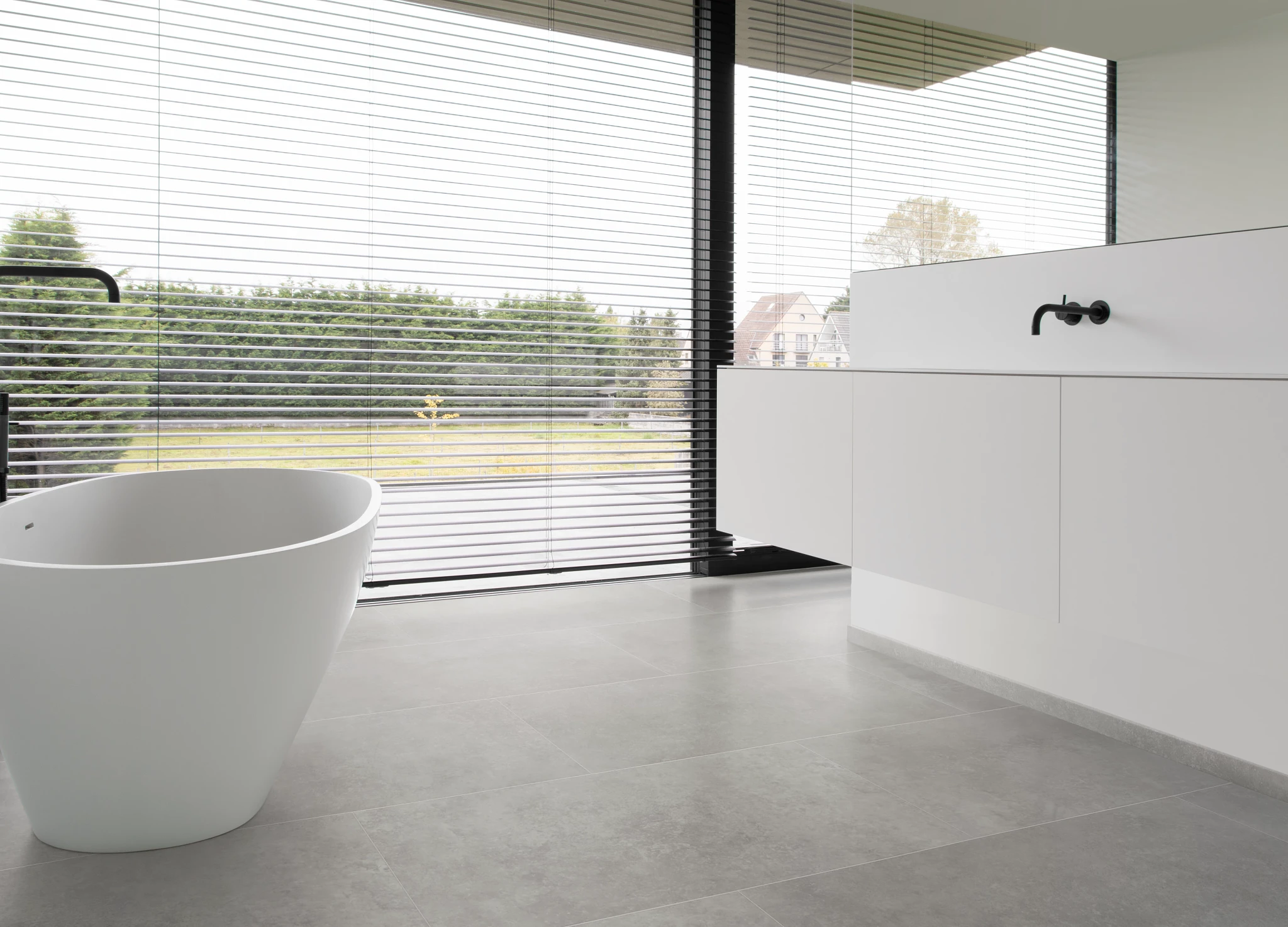 Modern bathroom with large windows featuring stone look luxury vinyl tile flooring in a light gray color