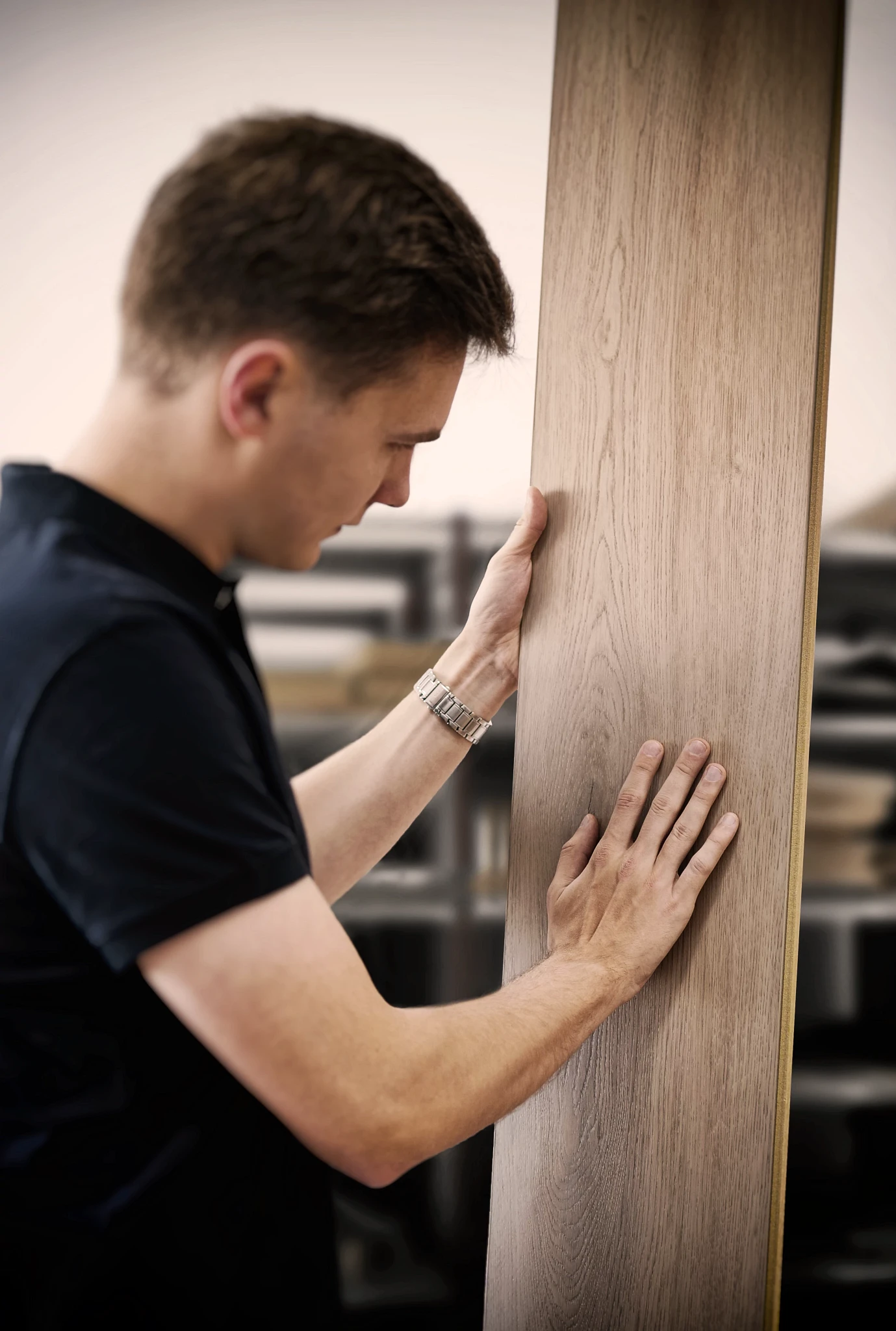Man examining wood look luxury vinyl plank flooring in a workshop setting