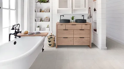Coretec Residential SPC Luxury Vinyl Tile Flooring in Modern Bathroom - 24x12 inch bathroom with luxury vinyl tile floor in a light stone look with a freestanding bathtub and wooden vanity