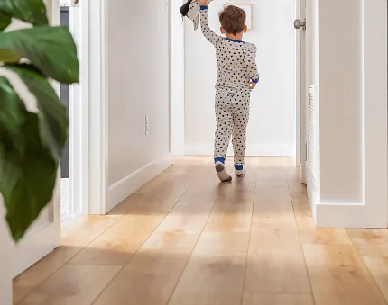 Wood Look Luxury Vinyl Plank Flooring in Hallway Scene Child walking on wood look luxury vinyl plank flooring in a bright hallway