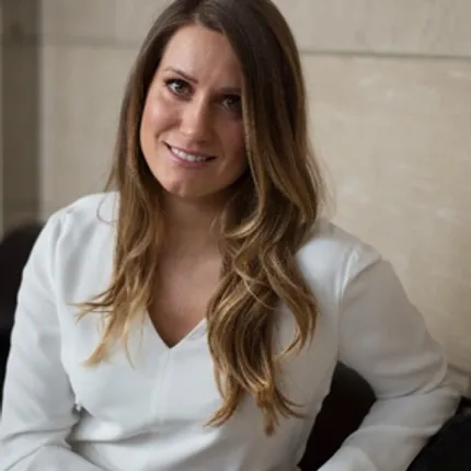 Professional woman in white blouse sitting indoors Woman in a white blouse sitting against a beige wall