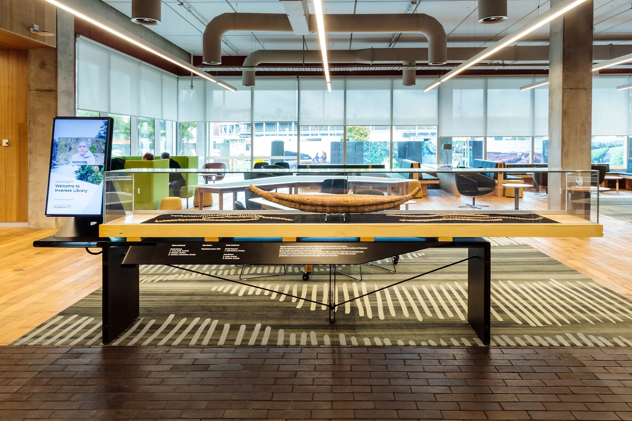 Cultural display within the University of Tasmania library, featuring a woven artefact, custom patterned carpet flooring and collaborative learning spaces.