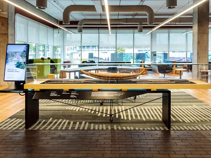 University of Tasmania Library Featuring Cultural Storytelling and Custom Flooring | Shaw Contract Cultural display within the University of Tasmania library, featuring a woven artefact, custom patterned carpet flooring and collaborative learning spaces.
