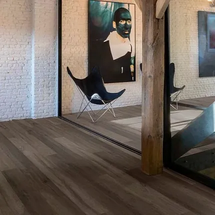 Luxury Vinyl Plank Flooring in Modern Living Room with Wood Look Design living room with luxury vinyl plank floor in a wood look design with a stylish black chair and  artwork on white brick walls