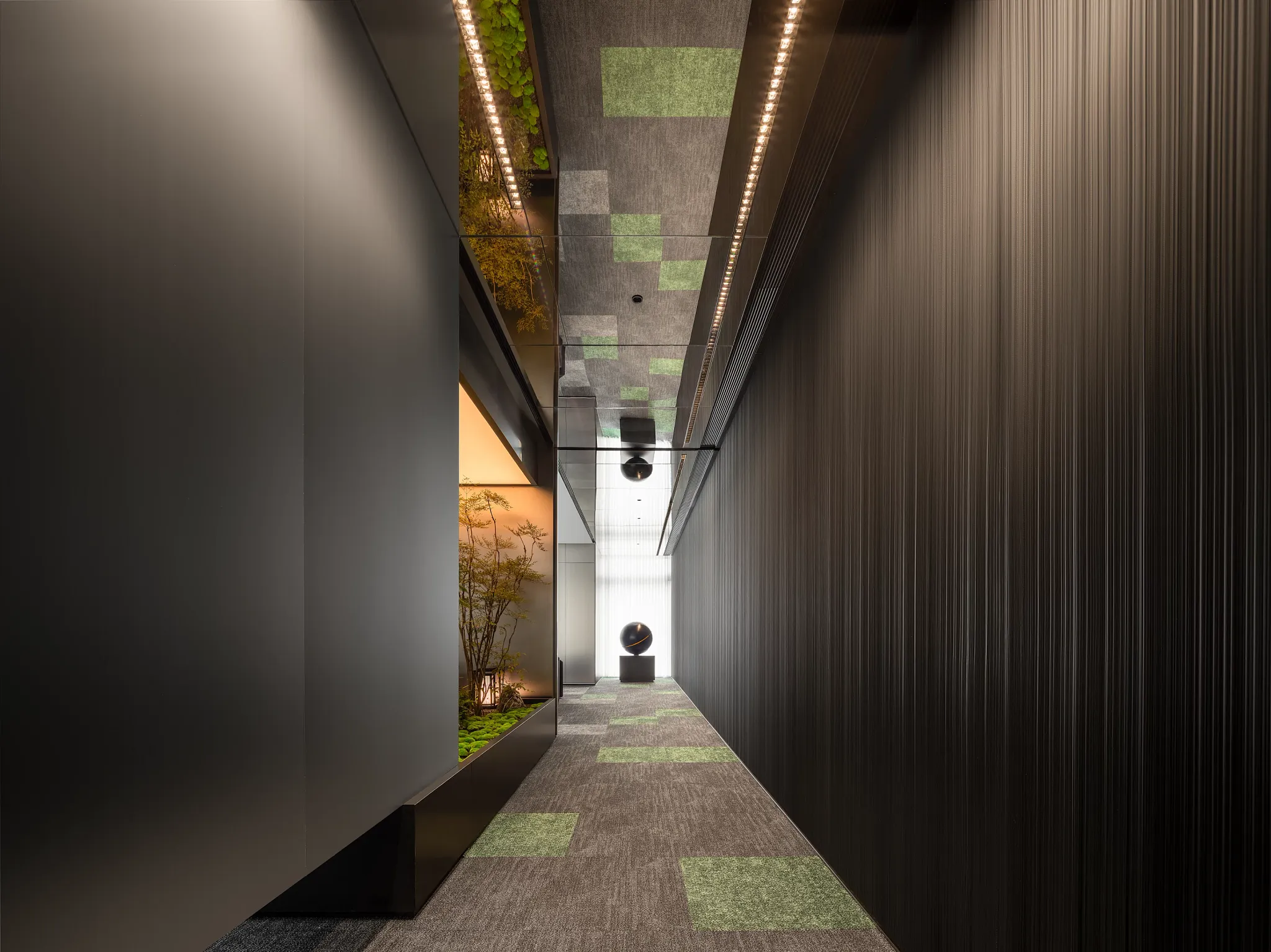 Modern hallway with commercial carpet tiles in gray and green, featuring sleek black walls and ceiling lighting