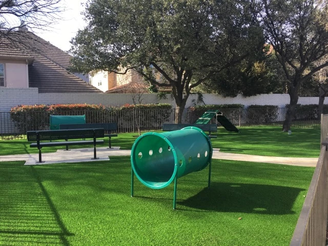 Outdoor playground with artificial grass flooring and green play equipment