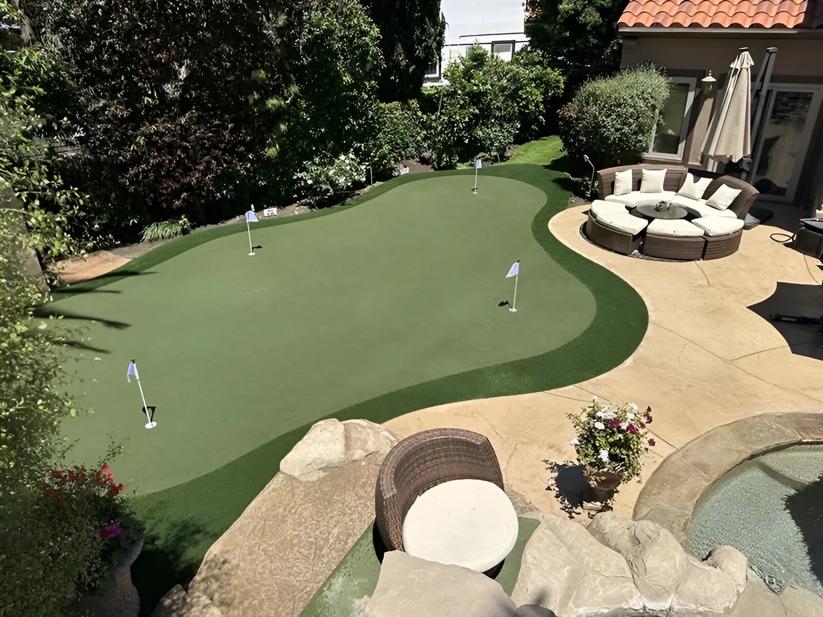 Backyard putting green with patio seating and landscaping