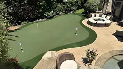 Outdoor putting green with comfortable patio area Backyard putting green with patio seating and landscaping
