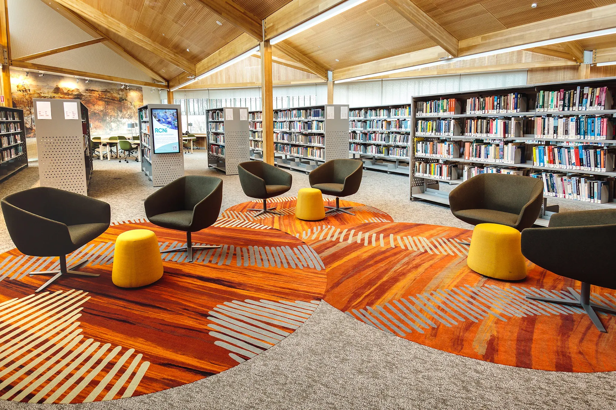 Custom carpet flooring installation within the University of Tasmania library, featuring organic patterns inspired by Indigenous storytelling and collaborative seating areas.