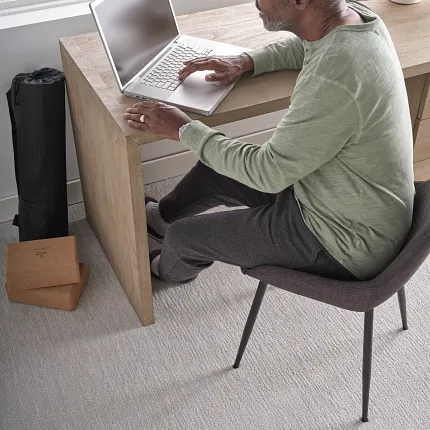 Light Gray Soft Surface Flooring in a Modern Home Office Setting Man working on a laptop at a wooden desk in a bright room with light gray soft surface flooring