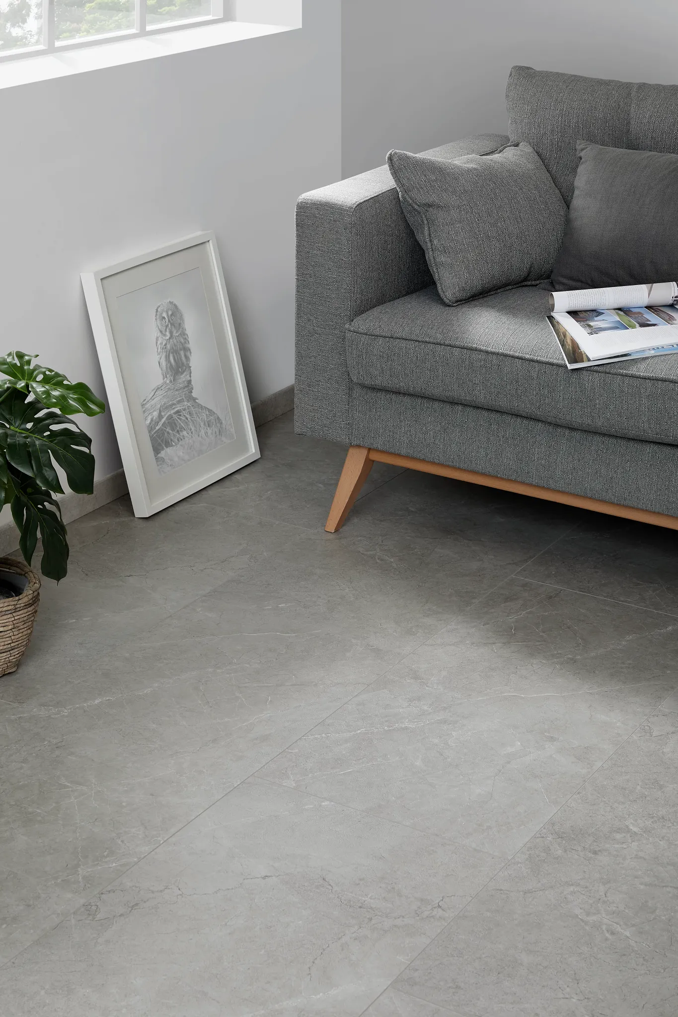 Modern living room with gray luxury vinyl tile flooring, gray sofa, and indoor plant