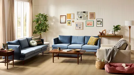 Contemporary living room with stylish brown wood-look flooring and modern furniture. Modern living room with brown wood-look flooring, featuring a beige armchair, a light wood coffee table, and a gray sofa with decorative pillows