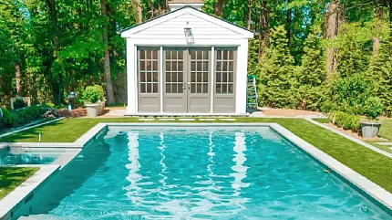 Serene backyard pool with lush landscape Outdoor swimming pool with surrounding greenery and pool house