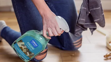 Easy maintenance for wood look luxury vinyl flooring Person cleaning wood look vinyl flooring with spray bottle and cloth