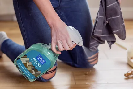 Easy maintenance for wood look luxury vinyl flooring Person cleaning wood look vinyl flooring with spray bottle and cloth
