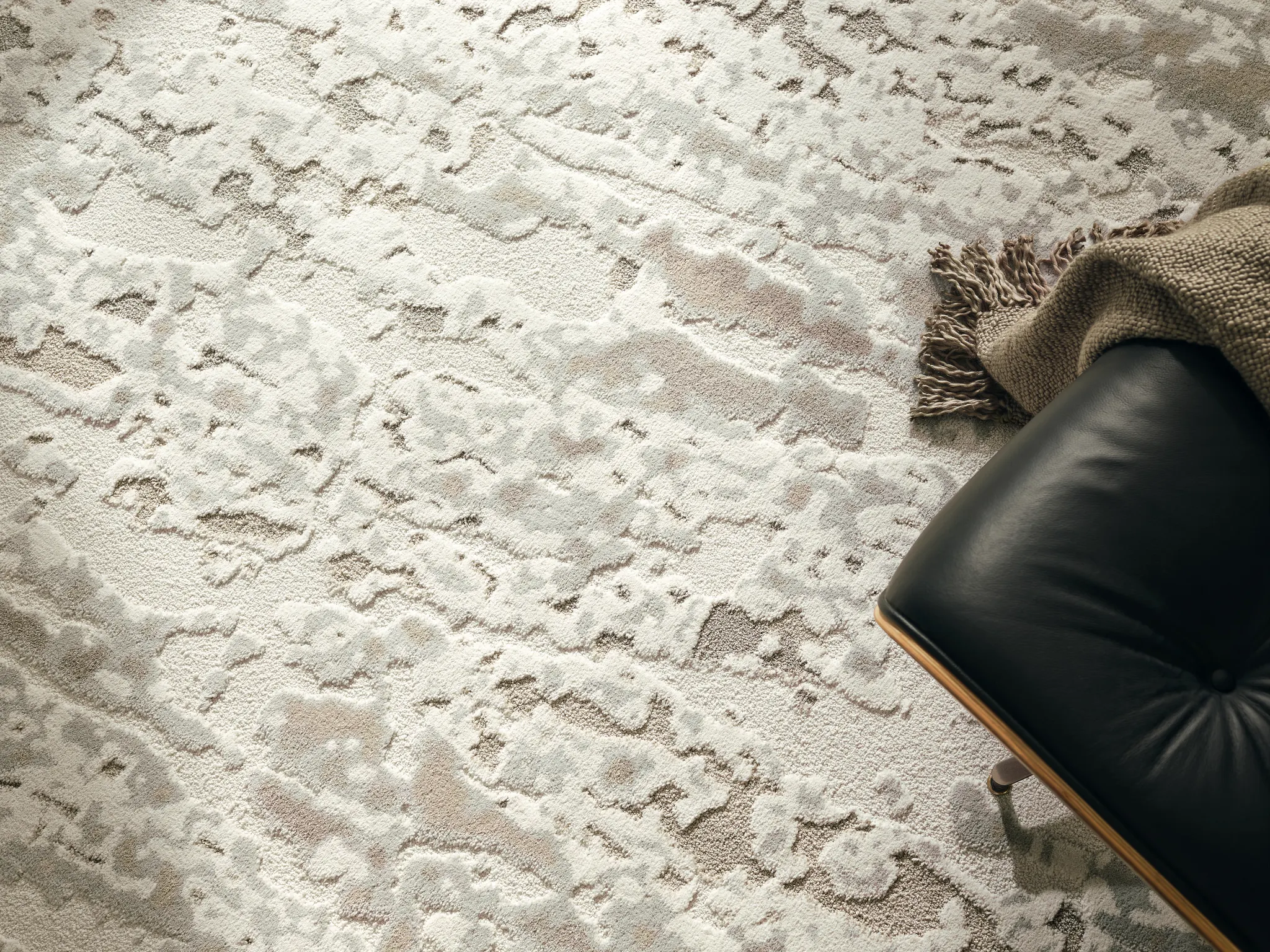 Textured carpet in neutral tones with a black leather chair