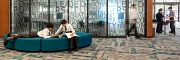 Modern Education Facility with Commercial Carpet Tile Flooring and Teal Seating Education facility with modern design featuring commercial carpet tile flooring in a geometric pattern, teal seating, and wooden wall panels