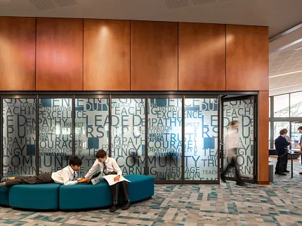 Modern Education Facility with Commercial Carpet Tile Flooring and Teal Seating Education facility with modern design featuring commercial carpet tile flooring in a geometric pattern, teal seating, and wooden wall panels