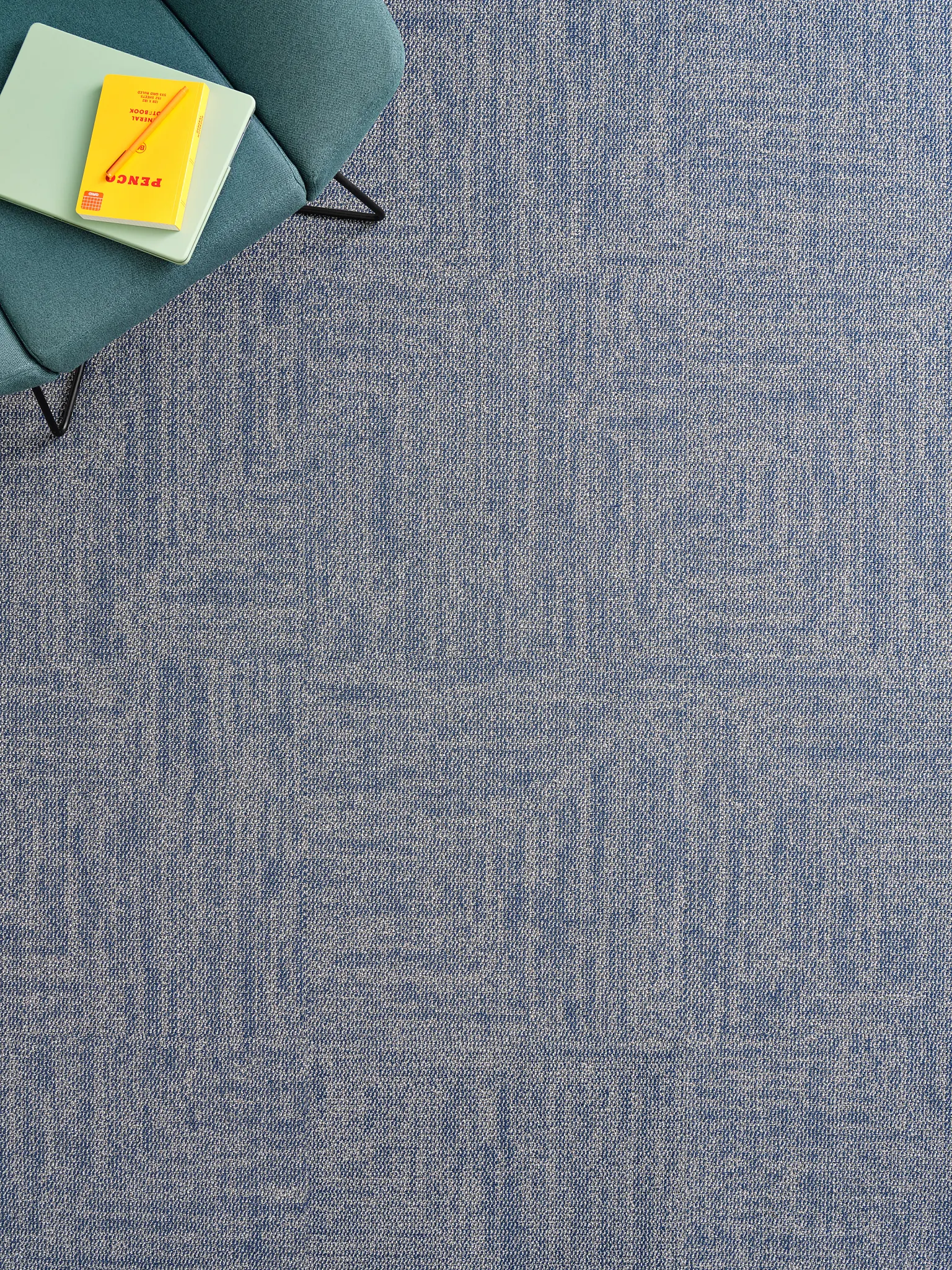 Blue carpet tile with chair and notebook