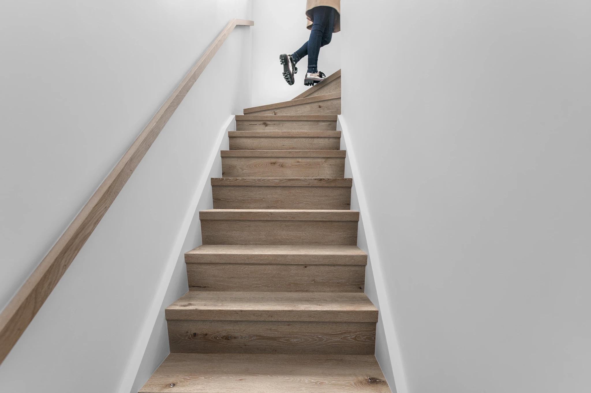 Modern staircase with wood look luxury vinyl plank flooring and a person walking up
