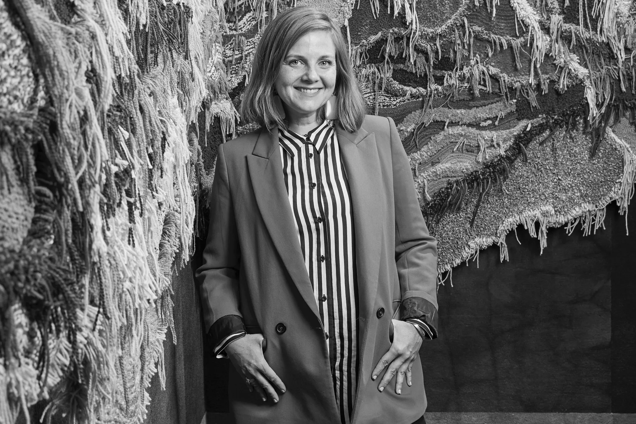Woman standing beside textured carpet samples in showroom