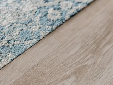 Light Wood Flooring with Blue and White Carpet Detail Close-up of a light wood flooring next to a blue and white textured carpet