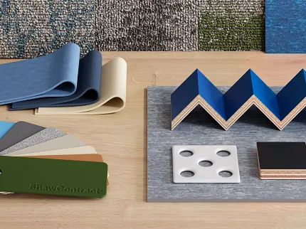 ShawContract Flooring Material Swatches in Blue, Beige, and Green Colors Swatch samples of ShawContract flooring materials including blue, beige, and green color options on a wooden surface