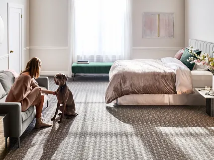 Elegant Bedroom Carpet Featuring Geometric Design and Neutral Tones Young woman in a beige robe interacting with a brown dog on a geometric patterned carpet in a well-lit bedroom