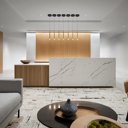 Modern workplace interior with commercial carpet tile flooring in 18x36 inch dimensions, featuring a sleek reception area with a marble counter and contemporary furniture.