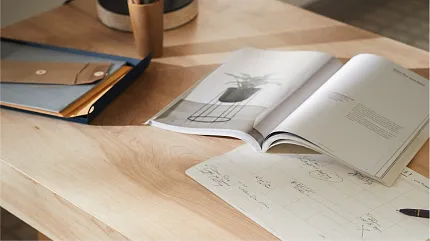 sketches and drawings in a book Natural toned wood table open to sketches and drawings