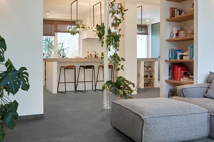 Dark Stone Look Luxury Vinyl Tile Flooring in Modern Living Room Modern living room with dark stone look luxury vinyl tile flooring, featuring a cozy gray sofa and indoor plants