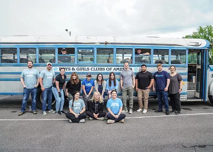 Shaw Floors Volunteers at Boys & Girls Club Shaw Floors associates volunteering and posing in front of a Boys & Girls Club bus during a community outreach event