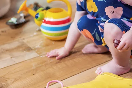 Durable and Waterproof Wood Look Luxury Vinyl Plank Flooring for Residential Spaces Young child playing on wood look luxury vinyl plank flooring with a colorful watering can