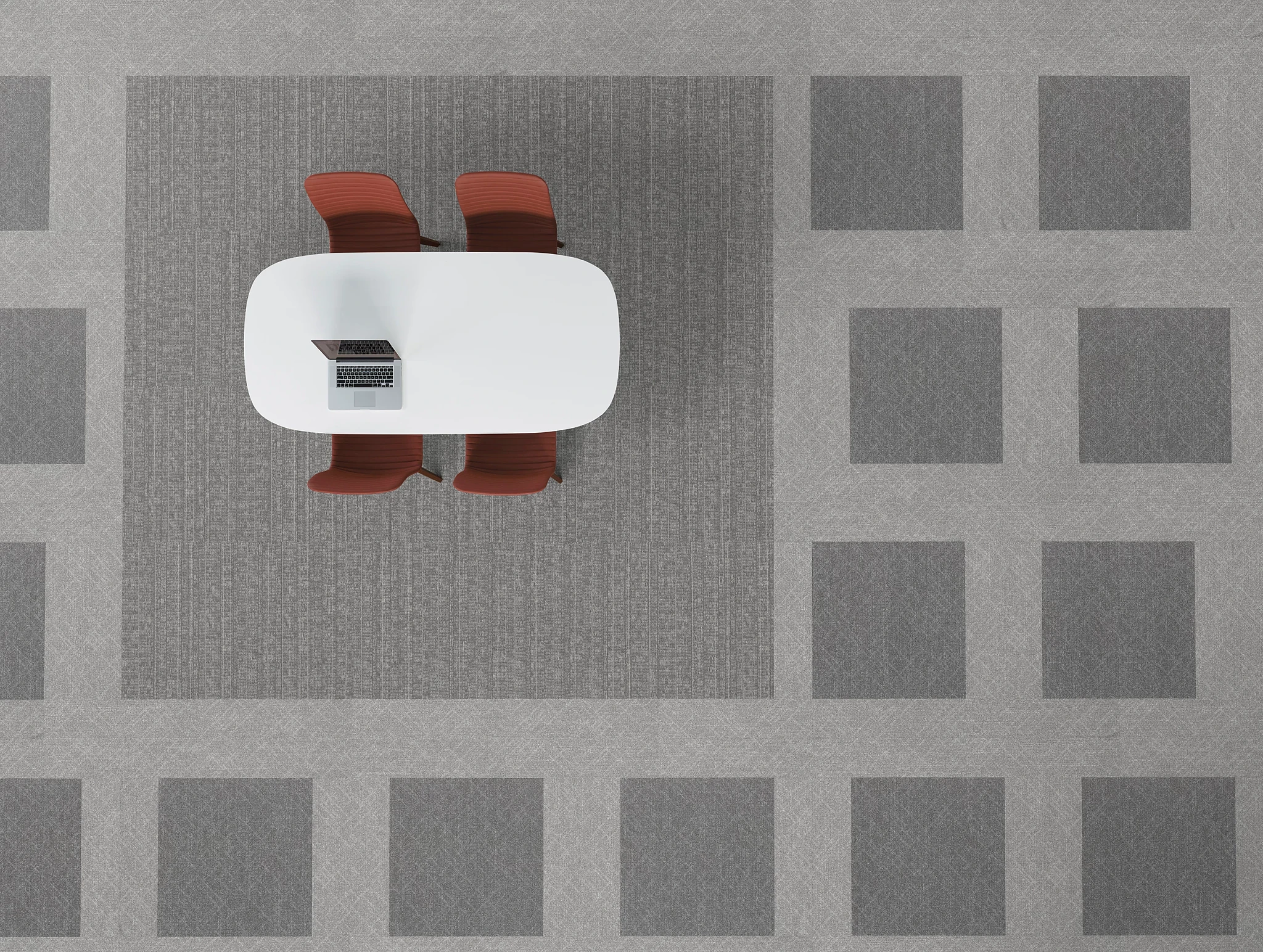 Overhead view of a modern office setup with a white oval table, two red chairs, and a laptop on a grey commercial carpet tile floor