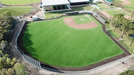 Baseball field with artificial grass and surrounding landscape Aerial view of a baseball field with artificial turf surrounded by fencing and trees