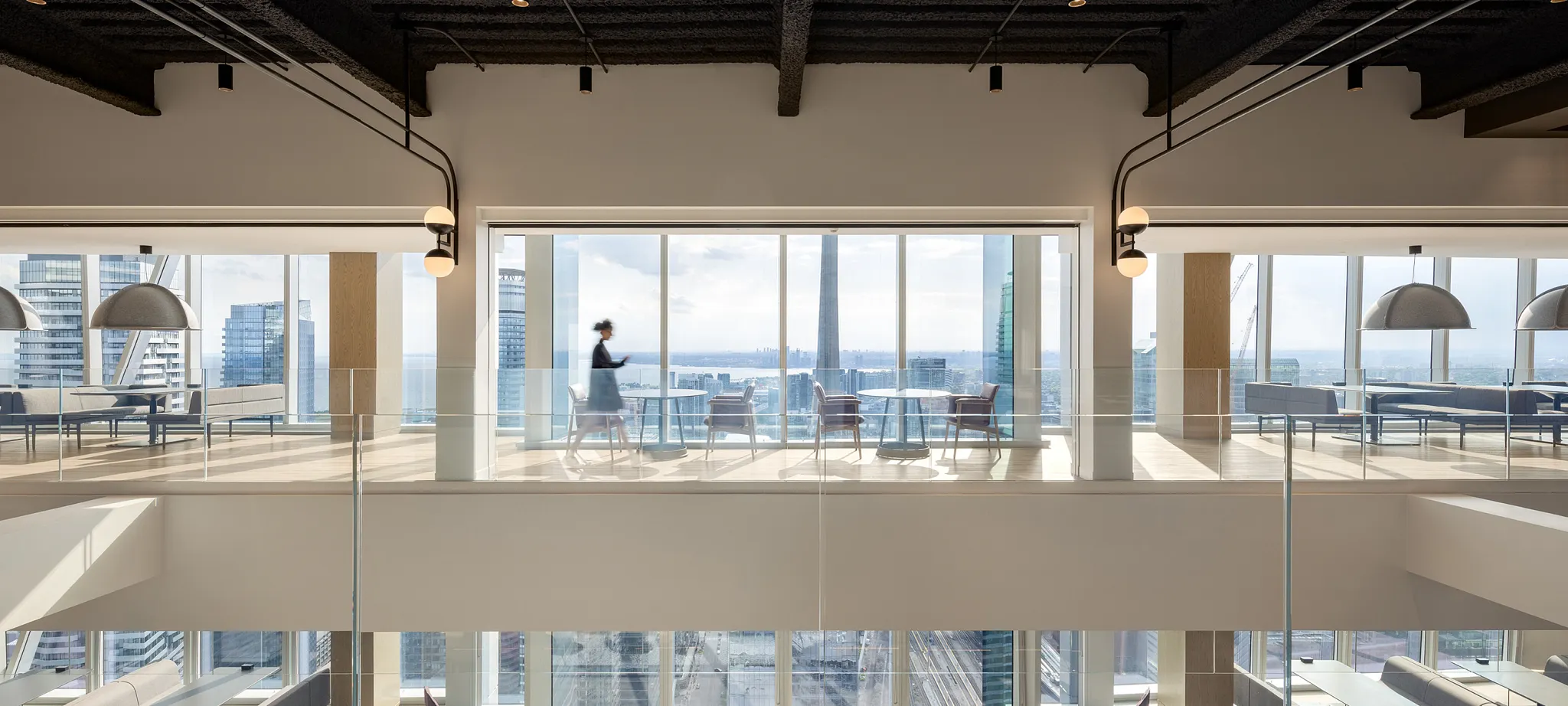 Modern office space with large windows and a person walking, showcasing a bright and open workplace environment
