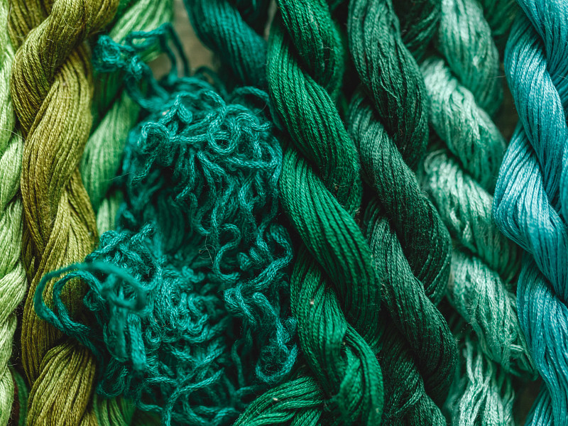 Close-up of various shades of green and blue yarns intertwined