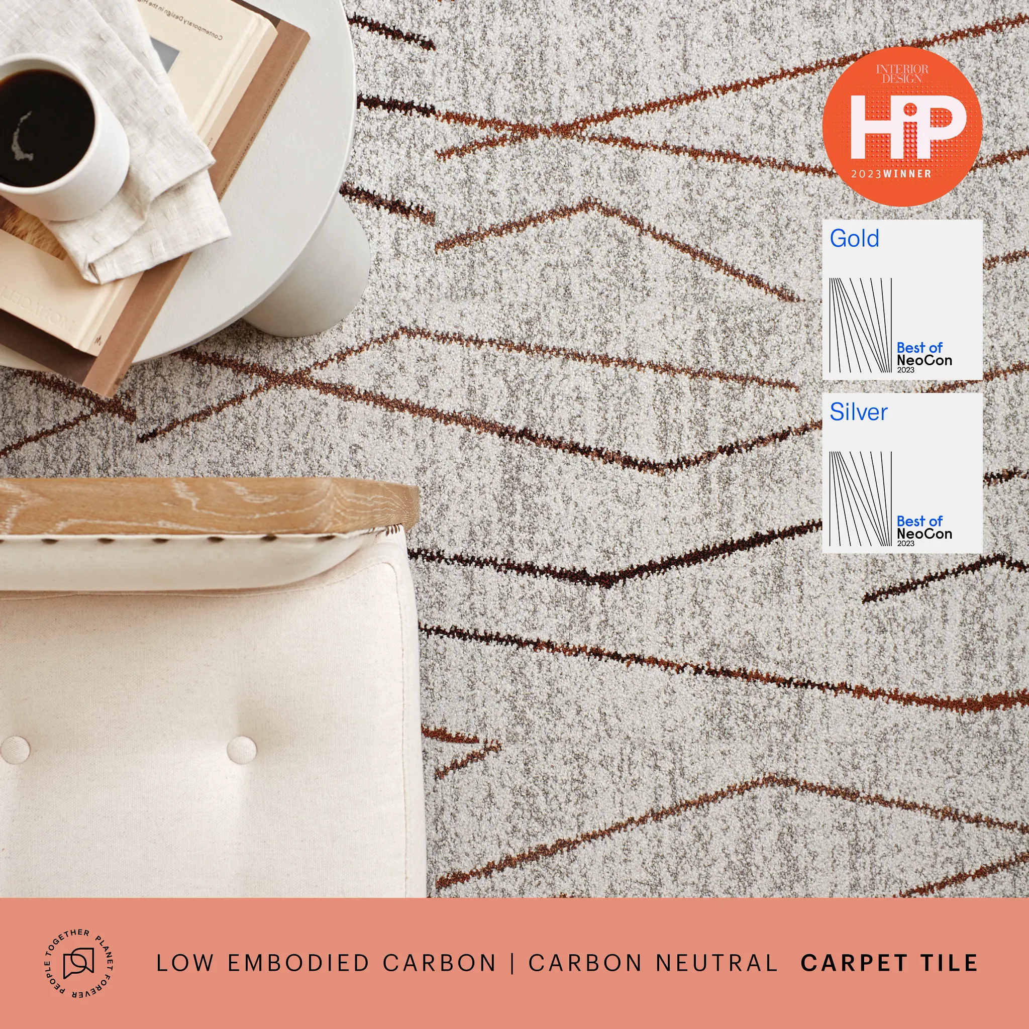 Modern commercial carpet tile with geometric pattern in shades of gray and brown, featuring a coffee table with books and a cup of coffee