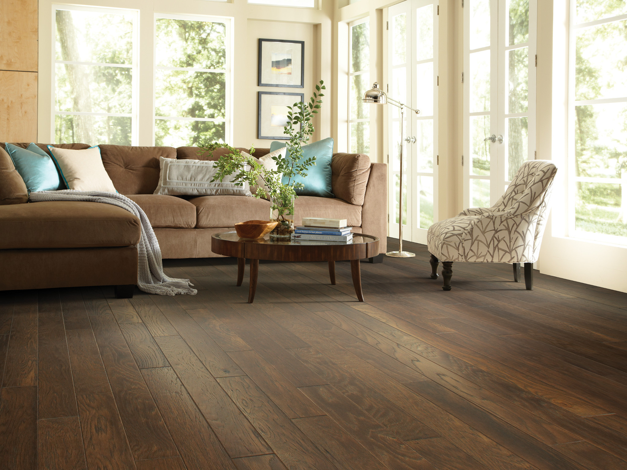Warm hardwood flooring in a sunlit living room with comfortable neutral furnishings