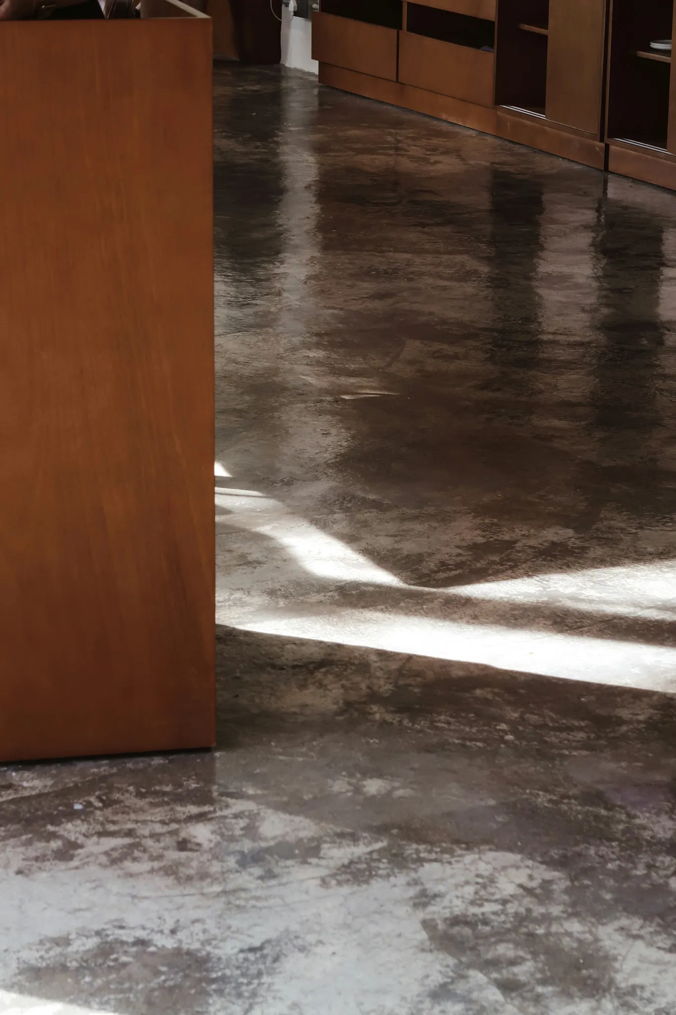 Floor preparation process with adhesive removal tool and worn sneakers visible