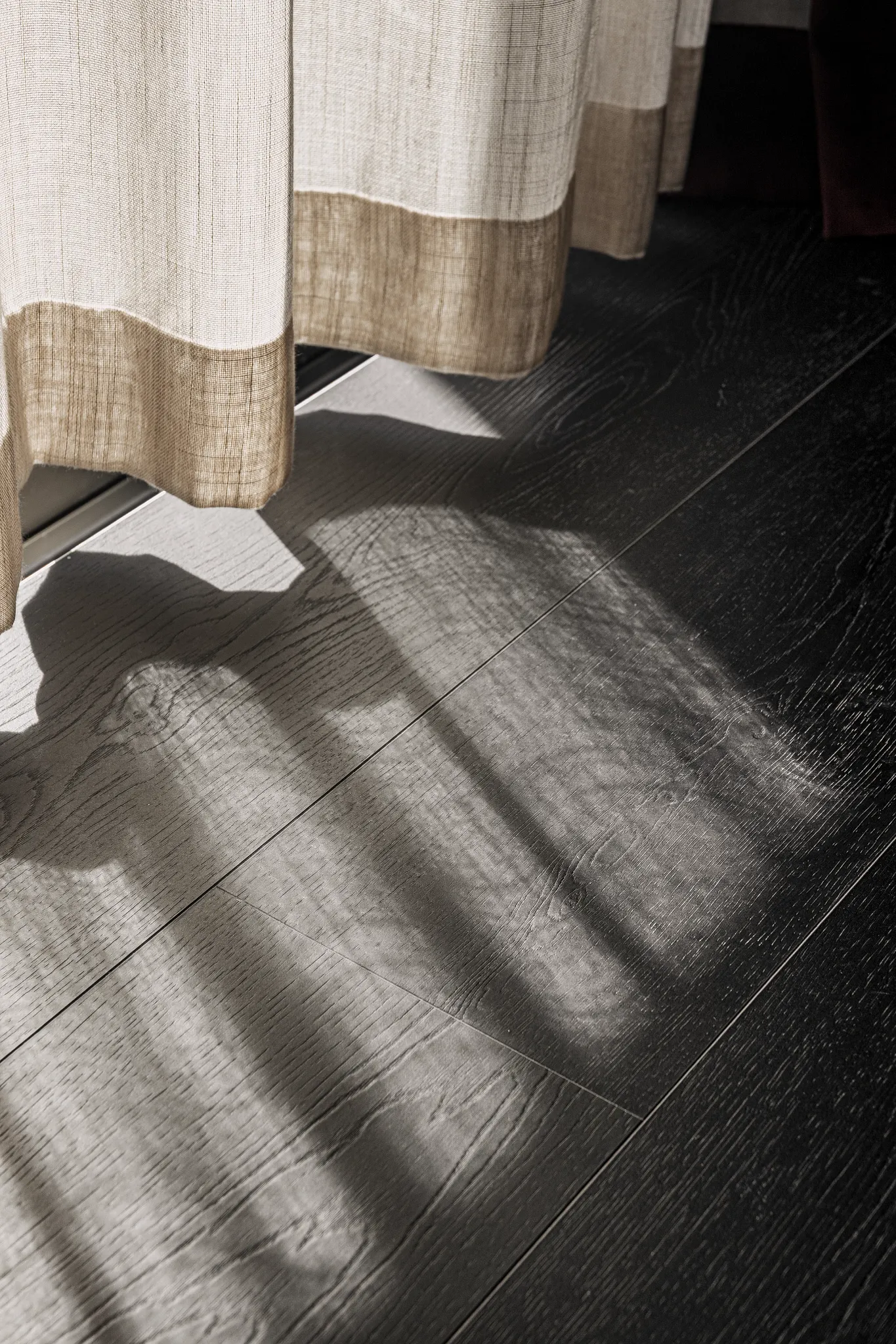 Close-up black wooden Coretec floor with curtain 