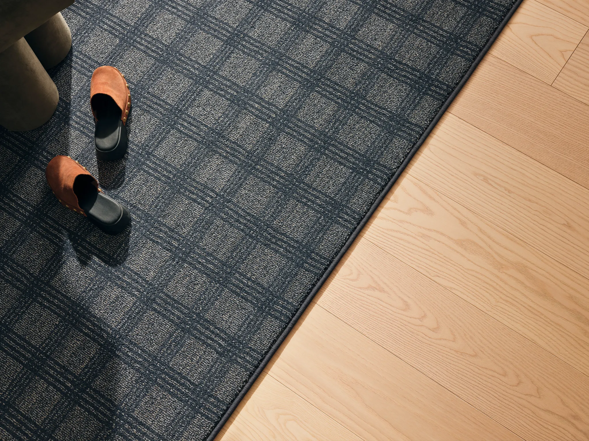 Blue and beige checkered carpet with light hardwood flooring and brown shoes