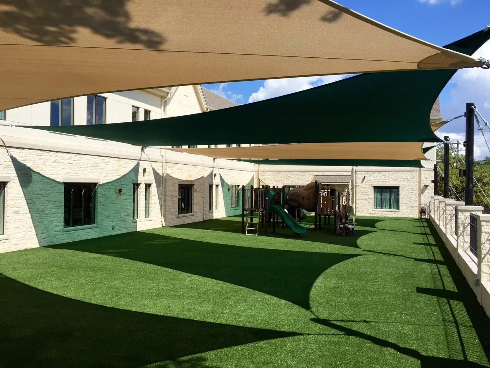 Outdoor playground with artificial grass and shade sails