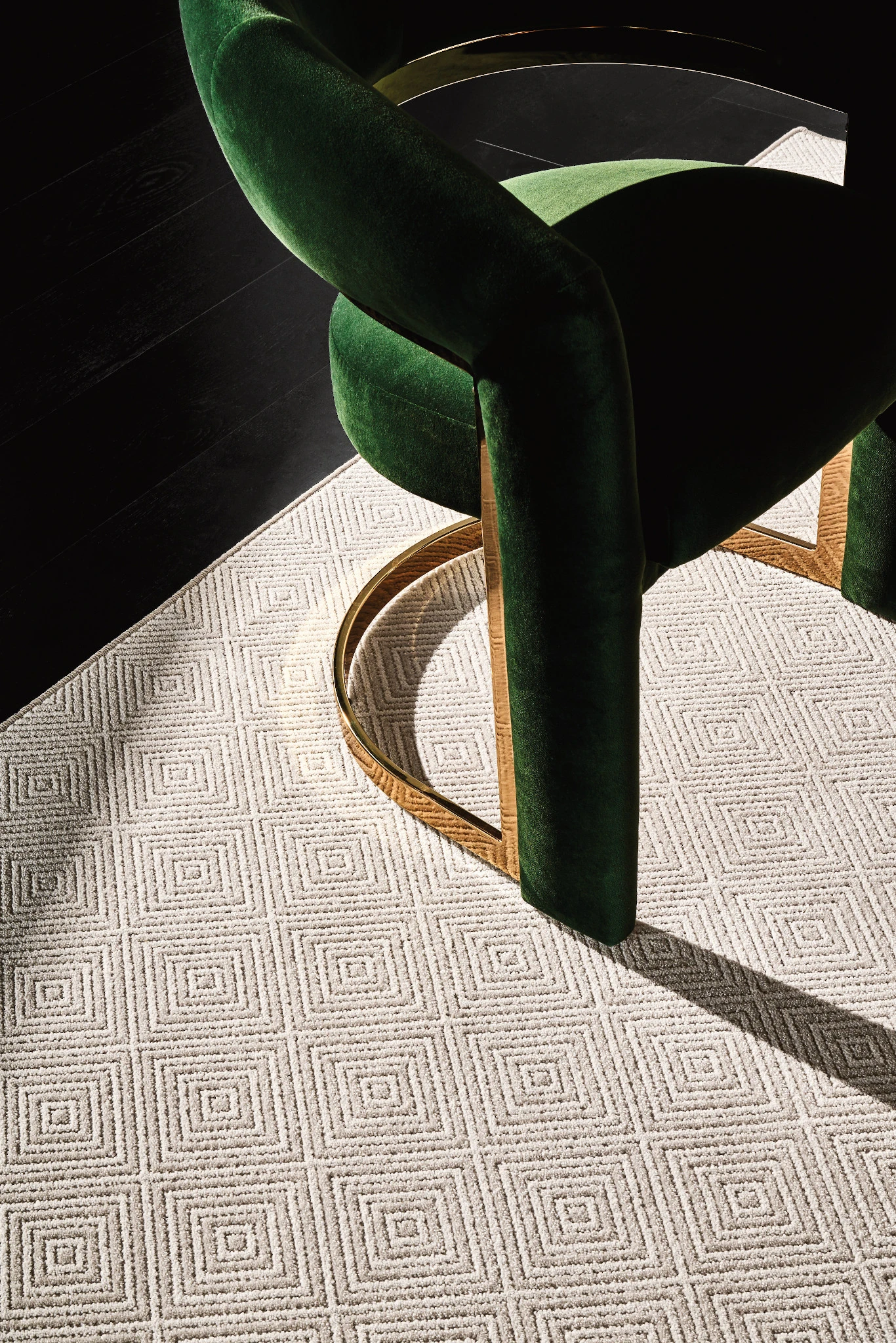 Luxurious green velvet chair on geometric patterned broadloom carpet in a modern living room setting